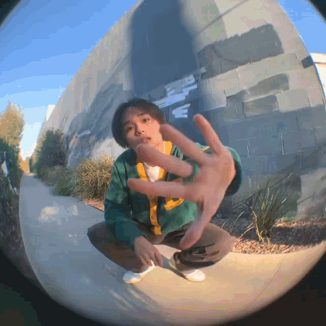 a fisheye lens shows a person squatting down with their hand outstretched