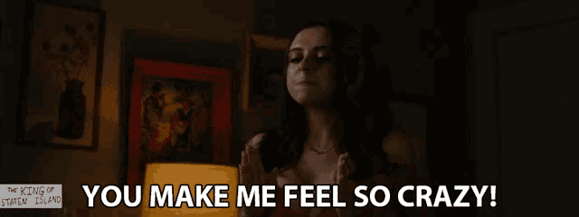 a woman in a red bra stands in front of a lamp and a sign that says " you make me feel so crazy "