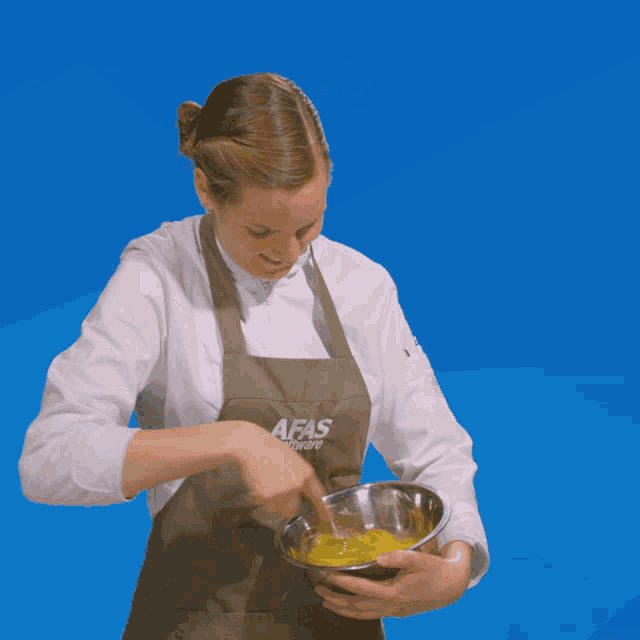 a woman wearing an apron that says afas software is mixing something in a bowl
