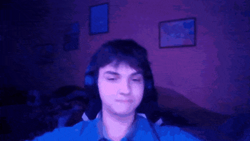 a man wearing headphones is sitting in a dark room with his eyes closed .