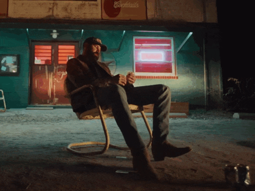 a man sitting in a chair in front of a cocktails sign