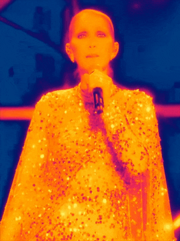 a woman in a sequined dress is singing into a microphone with a blue background