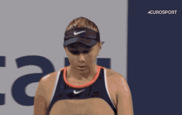 a woman wearing a nike visor stands in front of a eurosport sign