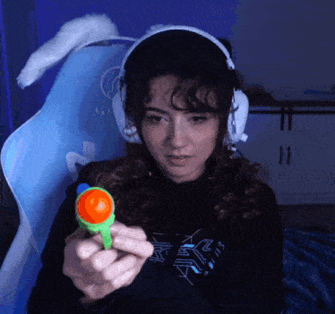 a woman wearing headphones is holding a small toy in her hand