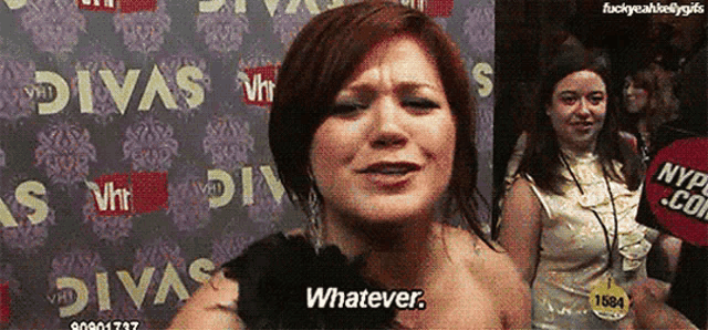 a woman is standing in front of a wall that says ' whatever '