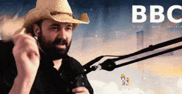 a man in a cowboy hat stands in front of a microphone with bbc written on the bottom