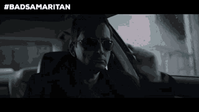 a man is sitting in a car talking on a cell phone .