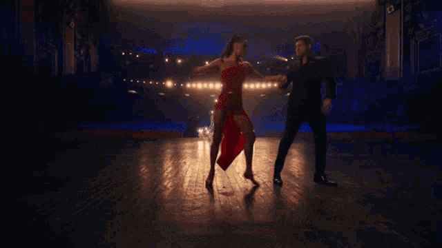 a man and woman are dancing in front of a christmas tree .