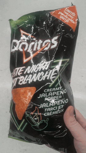 a person is holding a bag of creamy jalapeno popper doritos