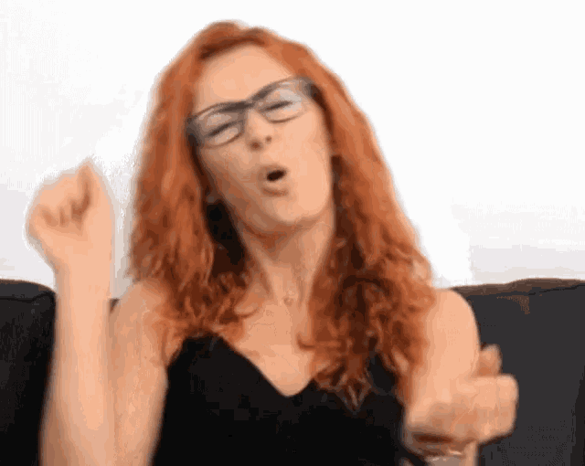 a woman with red hair is wearing glasses and a black top