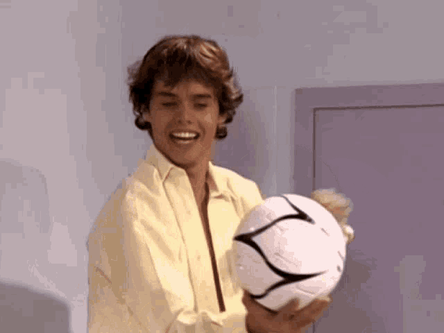 a man in a yellow shirt is holding a soccer ball in his hands