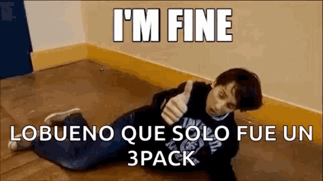 a boy is laying on the floor giving a thumbs up sign .