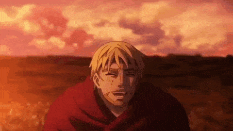a man with blonde hair is standing in a field with a sunset in the background and smiling .