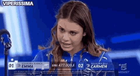 a woman in a blue shirt is sitting in front of a microphone and the words viperissima are on the screen