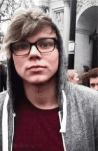 a young man wearing glasses and a hoodie .