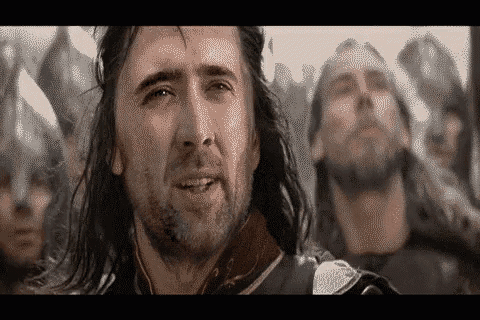a man with long hair is standing in front of a crowd of men .