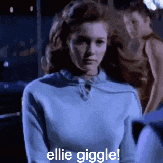 a woman is wearing a blue sweater and says ellie giggle !