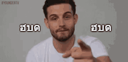 a man with a beard is wearing a white shirt and pointing at something .