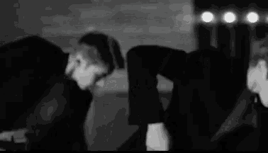 a black and white photo of two men in suits and ties dancing .