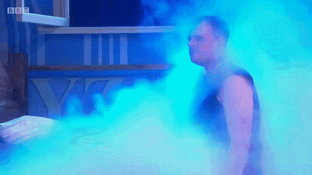 a man is standing in a room with blue smoke coming out of the window
