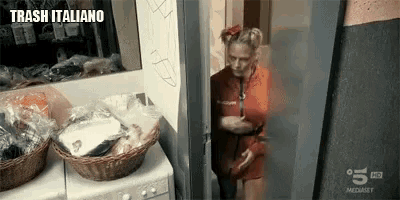 a woman is standing in a laundry room next to a washing machine and a basket .