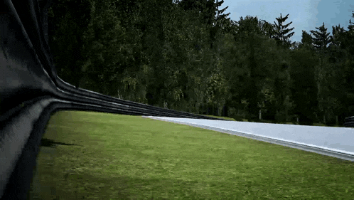 a race car is driving down a race track with trees in the background