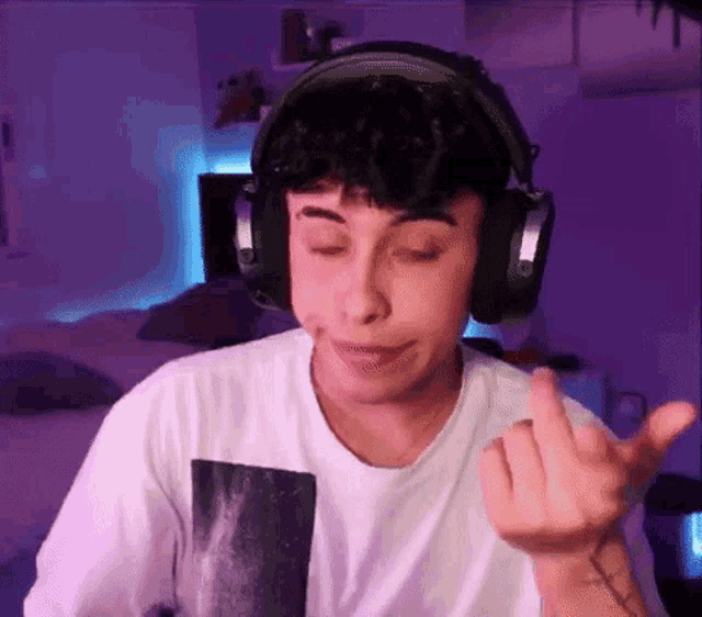 a young man wearing headphones is making a face and giving the middle finger .