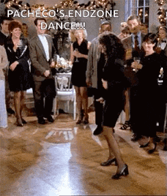 a woman in a black dress is dancing on a dance floor in front of a crowd of people .