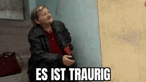 a woman is sitting on a set of stairs next to a wall with the words `` es ist traurig '' above her .