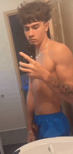 a shirtless man taking a picture of himself in a mirror
