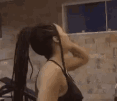 two women are doing exercises in a gym and one of them is throwing her hair in the air .