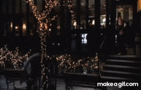 a man is standing on a balcony with a christmas tree in the background and screaming .