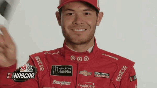 a man wearing a red racing suit and a hat is smiling .