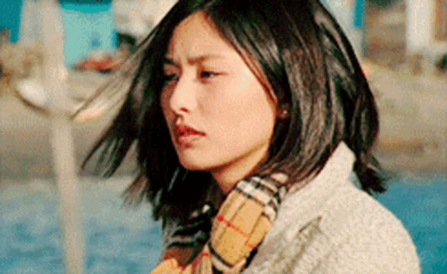 a woman wearing a plaid scarf and a white jacket