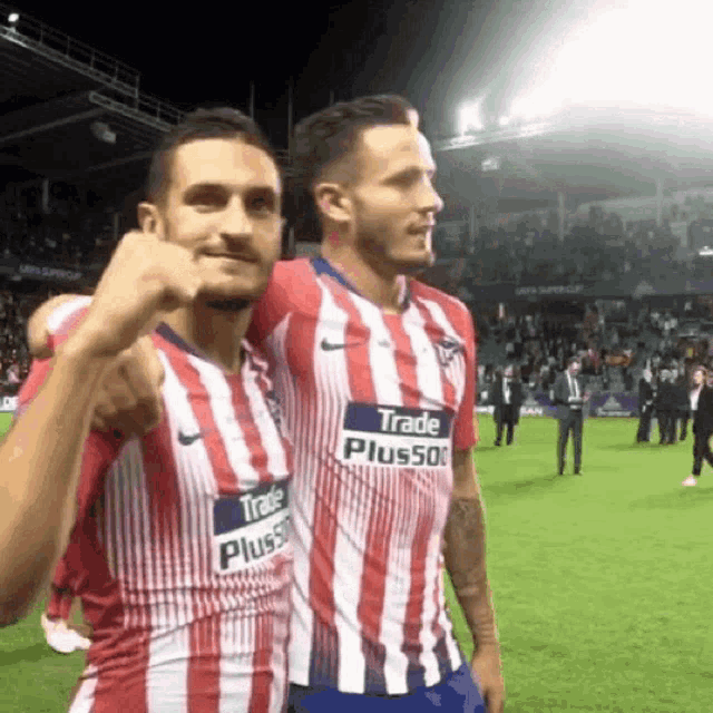 two soccer players wearing red white and blue striped jerseys with trade plus500 on the front
