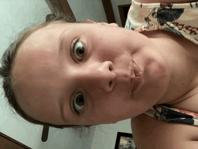 a close up of a girl 's face with a floral top on