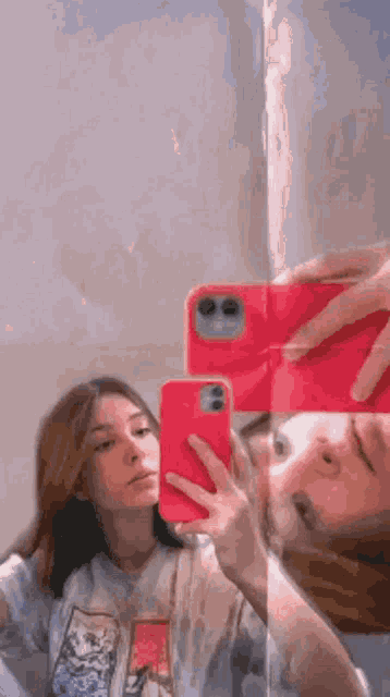 a girl is taking a selfie in a mirror with a red phone .