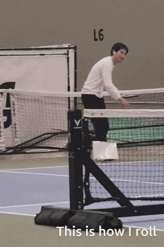 a man stands on a tennis court with a sign that says l6