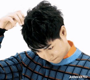a man in a plaid sweater is scratching his hair