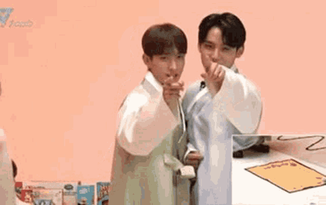 two young men are standing next to each other and pointing at something .