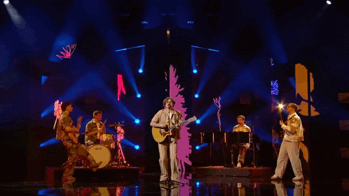 a man singing into a microphone while playing a guitar on a stage