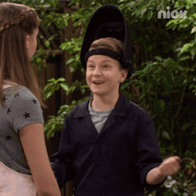 a boy wearing a welding helmet is talking to a girl on nickelodeon