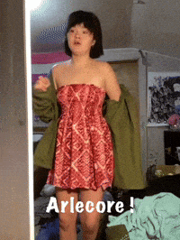 a woman in a red dress is standing in front of a mirror with the words arlecore written below her