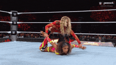 two women are wrestling in a ring with peacock on the bottom right