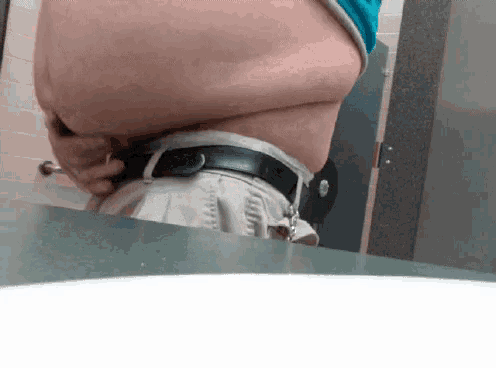 a man is taking a picture of his stomach in a public restroom
