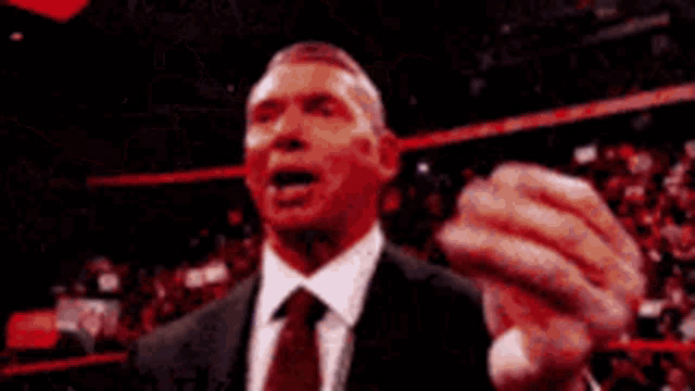 a man in a purple suit and tie is holding a microphone and talking into it .