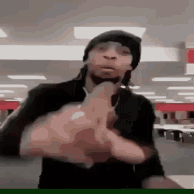 a man wearing a hat and sunglasses is giving the middle finger in a store .