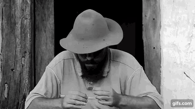a man with a beard wearing a hat is sitting in front of a door .