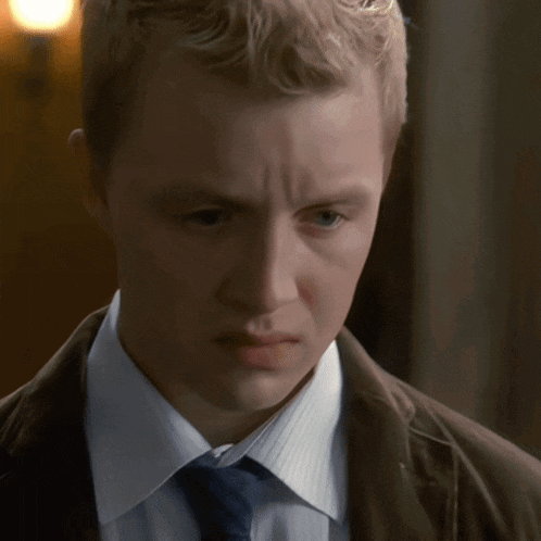 a young man in a suit and tie looks down