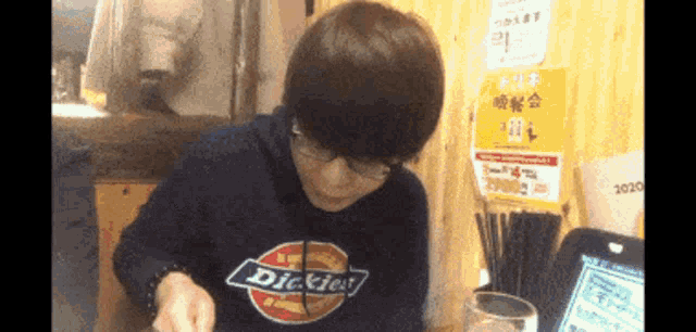 a person wearing a black dickies sweatshirt is eating